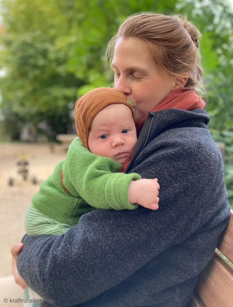 Eine Frau hält ein etwa zwei Monate altes Baby im Arm.