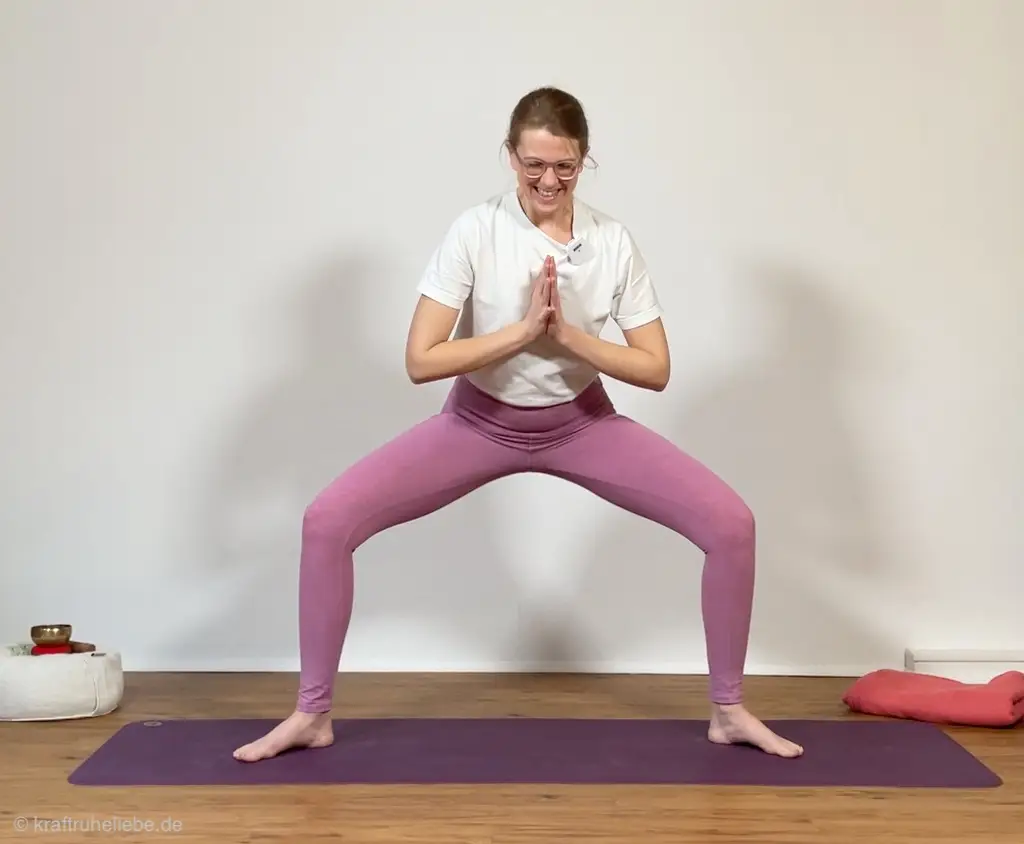 Utkata Konasana oder Goddess Pose: eine Frau in pinker Yogaleggings übt diese Haltung