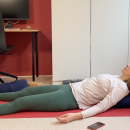 Eine Frau in Yogakleidung liegt auf dem Rücken in einer Entspannungsübung