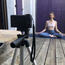 Eine Yogalehrerin sitzt vor einer Kamera und nimmt einen Onlinekurs auf