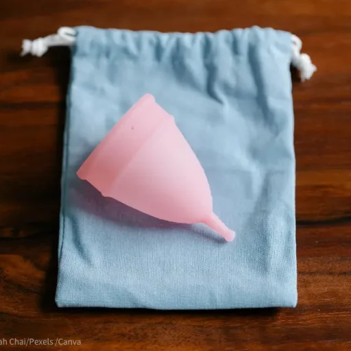 Schadet die Menstruationstasse dem Beckenboden? Bild einer rosa Menstruationstasse auf blauem Verpackungssäckchen.