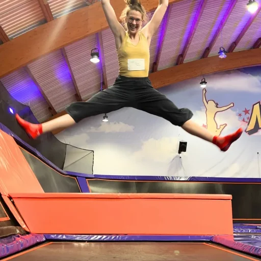 Schadet Trampolinspringen dem Beckenboden? Eine Frau zeigt einen Grätschsprung auf einem Trampolin.